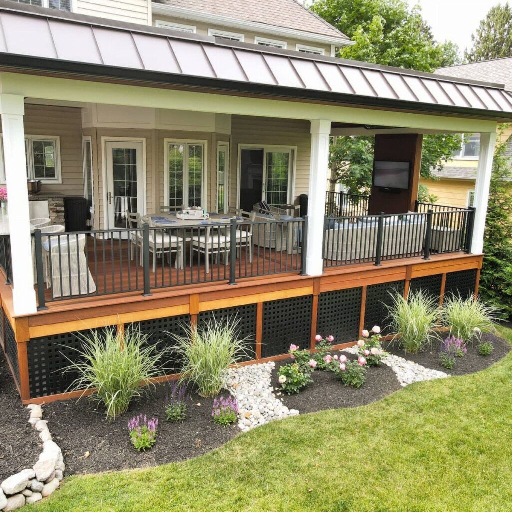 A covered wooden deck with a metal roof, outdoor furniture, and a landscaped garden area.