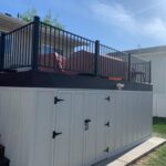 White wooden storage cabinets built into the space underneath a dark wooden deck.