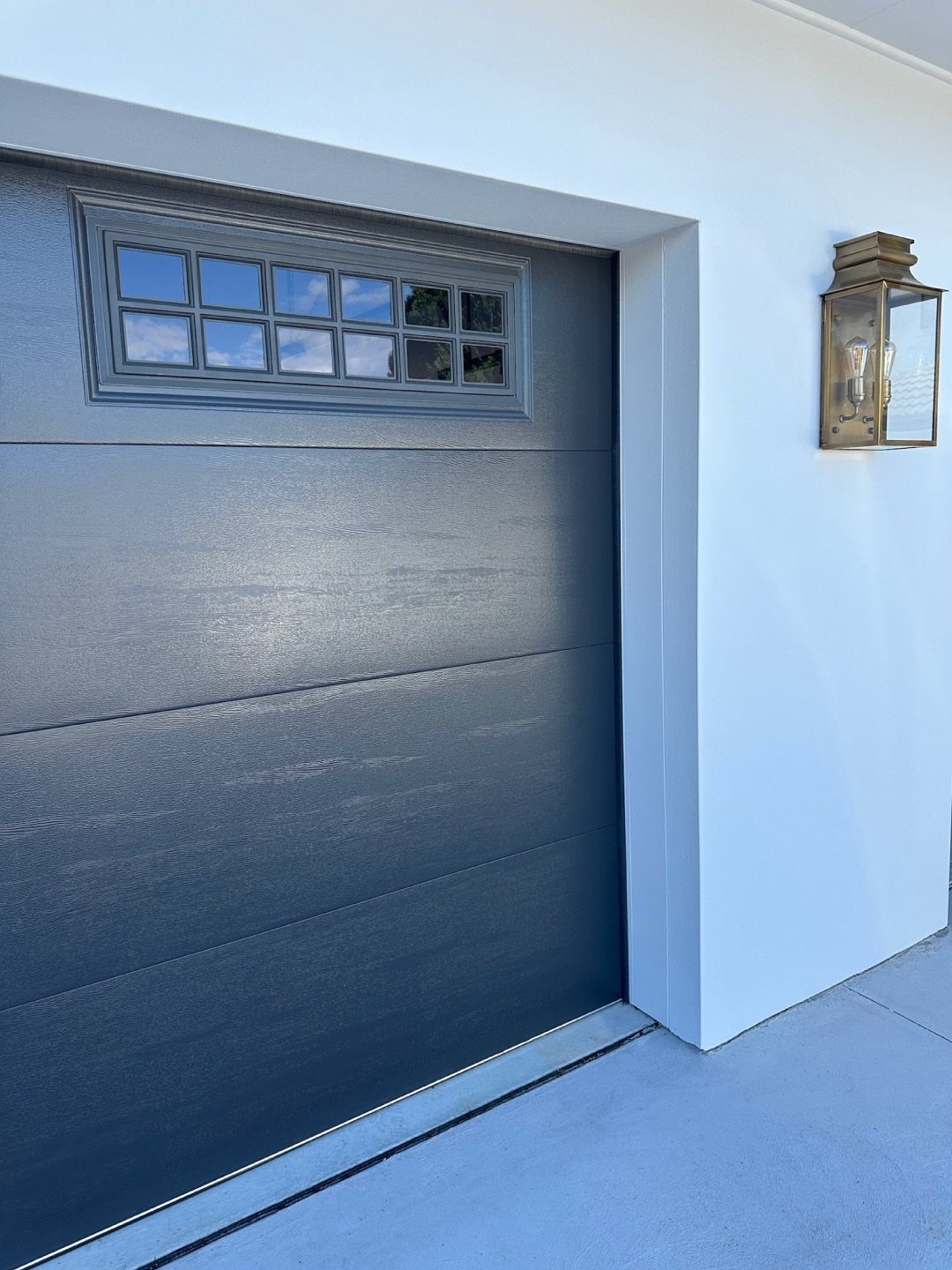 A dark blue garage door featuring a row of small glass window panes at the top.