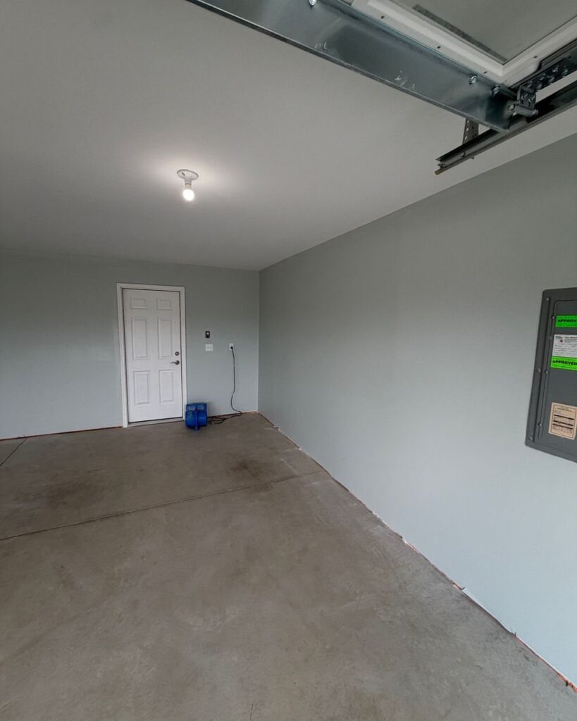 Empty garage interior featuring light grey painted walls and a smooth concrete floor.